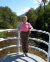 Nancy standing on footbridge over mountain river next to hotel